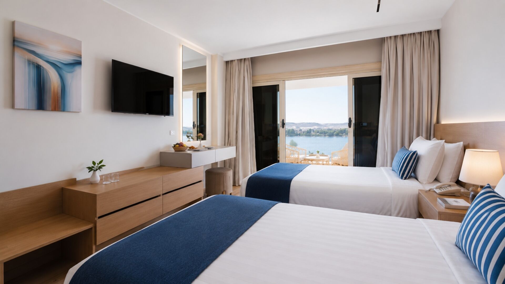 Habitación de hotel con dos camas, televisión, escritorio y vista al agua.