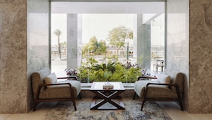 Una habitación moderna con un ventanal grande, dos sillones, una mesa de centro y vistas a la ciudad.