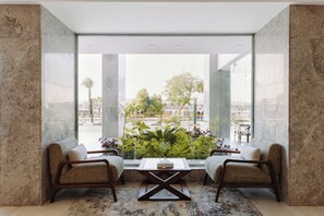 Una habitación moderna con un ventanal grande, dos sillones, una mesa de centro y vistas a la ciudad.