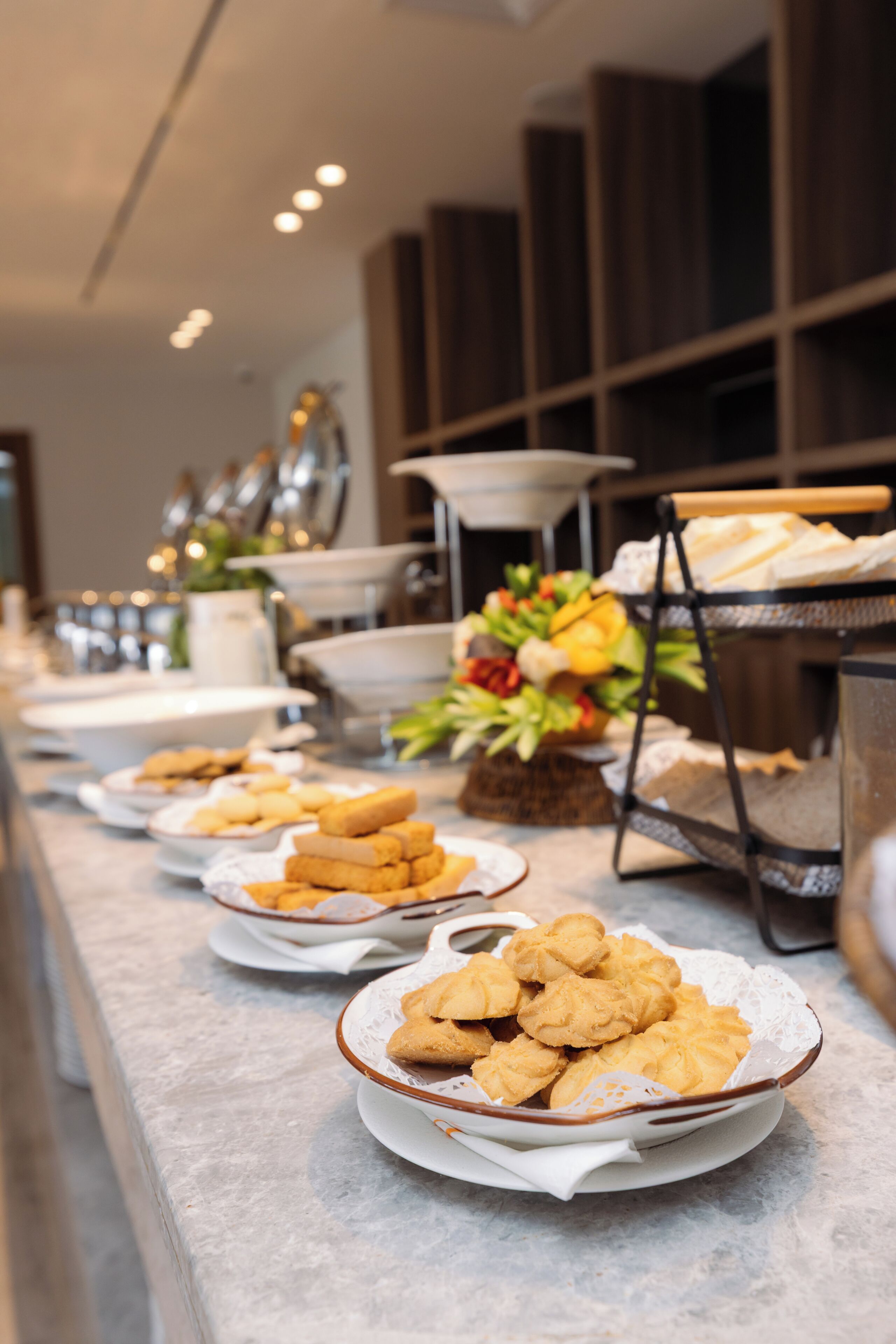 Montaje de bufé con diversos alimentos, incluyendo galletas y pasteles, dispuestos sobre una encimera de mármol.