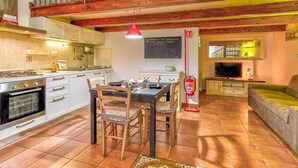 A kitchen with a dining table, chairs, a red pendant light, and a fire extinguisher. - Casa Il Maestro by Rentbeat (Civitavecchia)