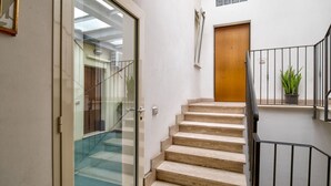 A staircase with a wooden door at the top, a glass door on the left, and a potted plant on the right. - Casa Il Maestro by Rentbeat (Civitavecchia)