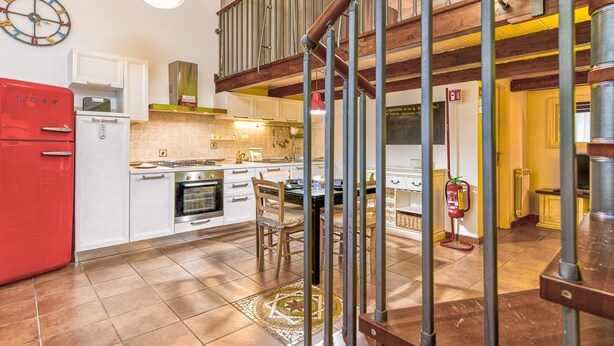 A kitchen with white cabinets, a red refrigerator, a stove, and a dining area with chairs. - Casa Il Maestro by Rentbeat (Civitavecchia)
