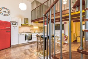 A kitchen with white cabinets, a red refrigerator, a stove, and a dining area with chairs. - Casa Il Maestro by Rentbeat (Civitavecchia)
