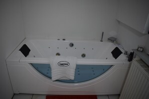 Eine weiße Badewanne mit blauer Innenseite, ein weißes Handtuch mit dem Schriftzug 'Coast Spas' und eine kleine Ablage mit Pflegeprodukten.