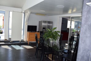 Eine moderne Küche mit Kühlschrank, Fernseher und Essbereich mit Stühlen und einem Glastisch.