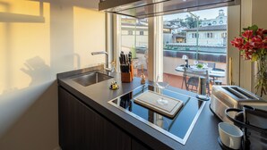 A modern kitchen with a large window, a built-in stove, and a coffee machine. - Luxury Apartment and Terraces - Medici Penthouse (Firenze)
