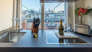 A modern kitchen with a large window, a sink, a wine bottle, and a toaster. - Luxury Apartment and Terraces - Medici Penthouse (Firenze)