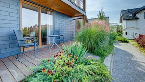 A modern house with a wooden deck, a glass door entrance, and a small outdoor seating area. - Ground Floor Holiday Studio, Gaski (Mielno)