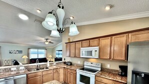 A modern kitchen with granite countertops, stainless steel appliances, wooden cabinets, and a central island. - Sunscape Palms - 3/2 with Golf Cart & Grill in The Village of St. James (St. James, The Villages)