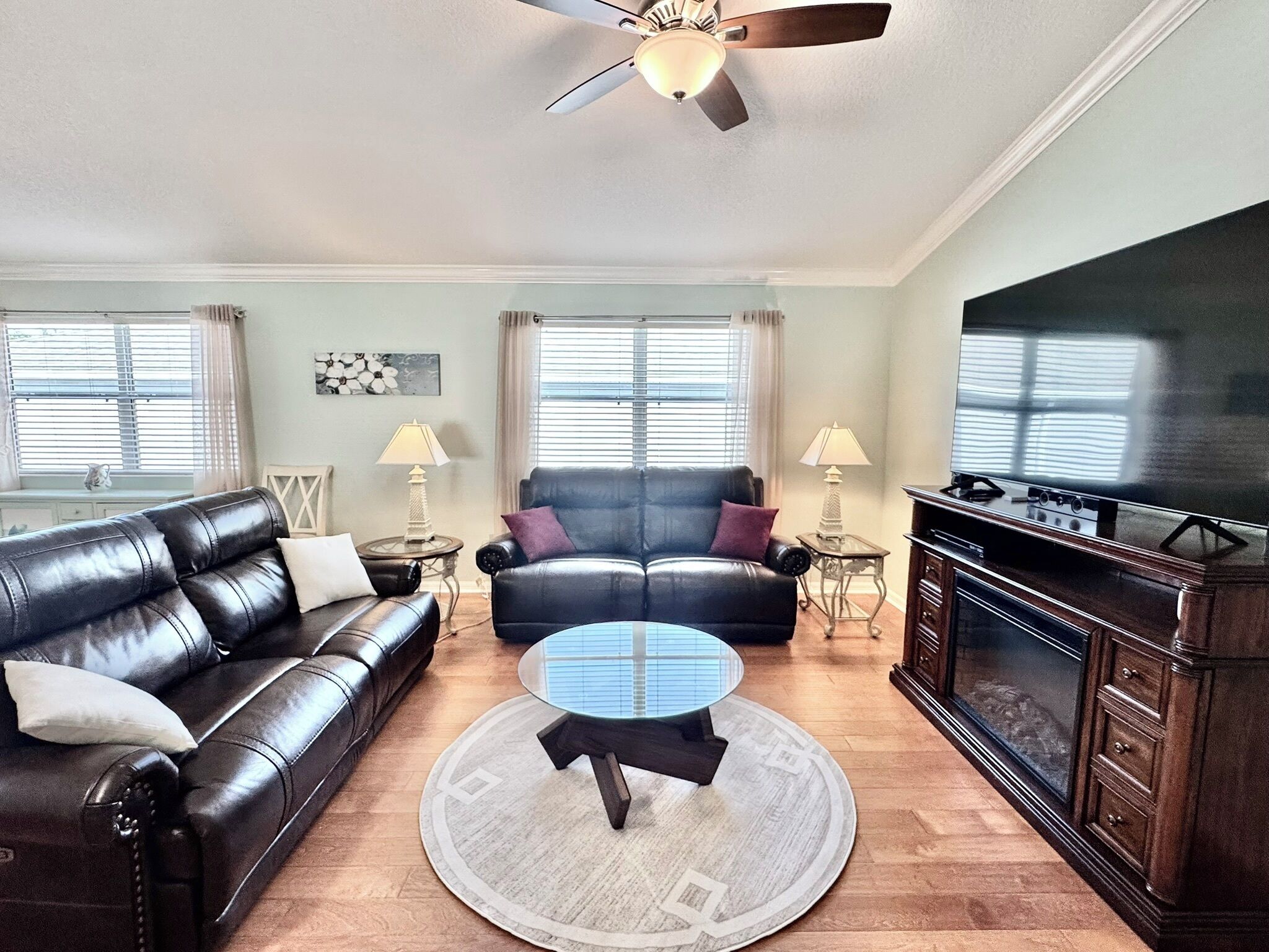 A living room with a leather sofa, a round coffee table, and a TV.