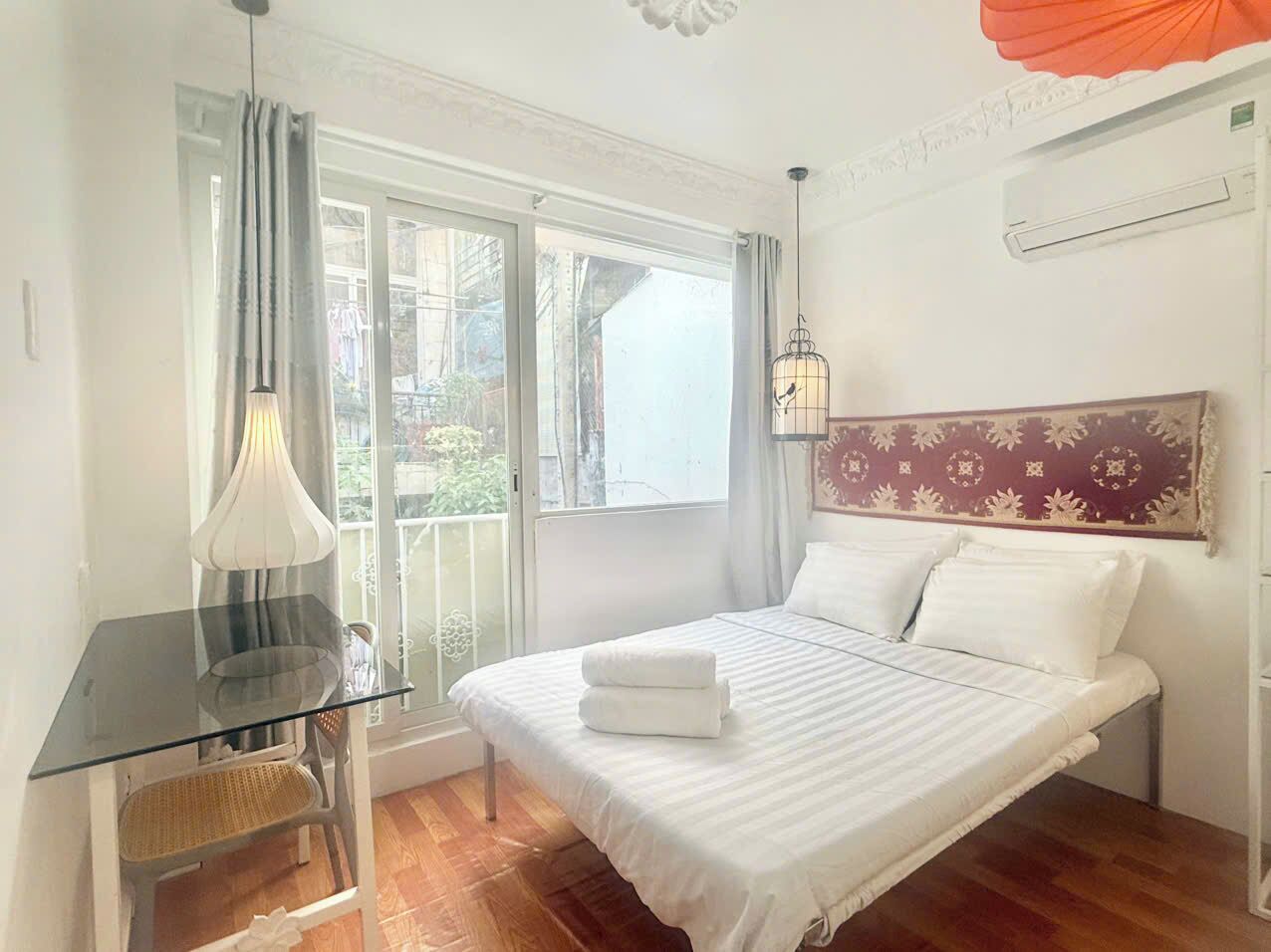 A bedroom with a bed, a desk, a chair, and a window with curtains.