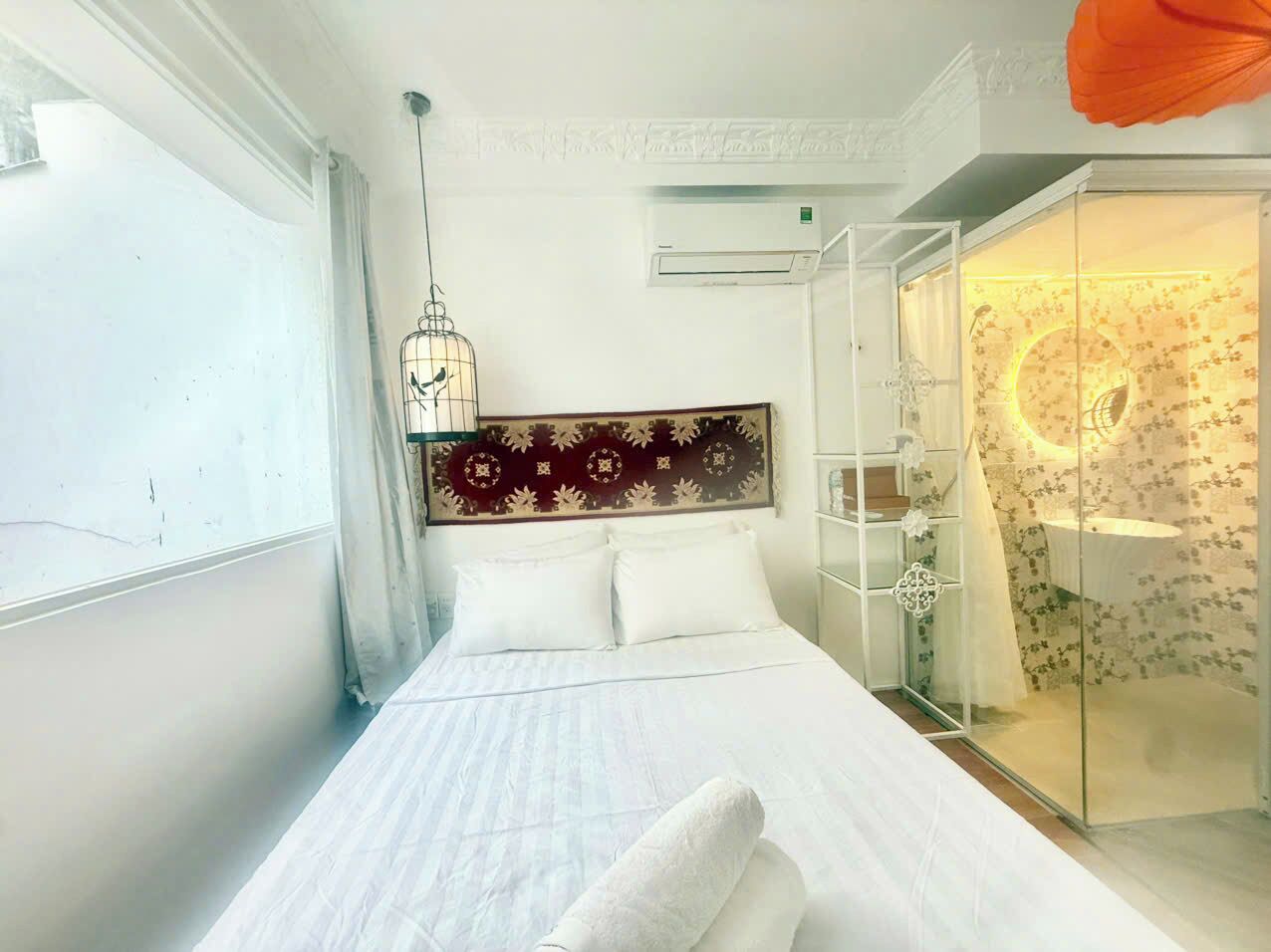Una habitación de hotel con cama, armario, ducha y ventana.
