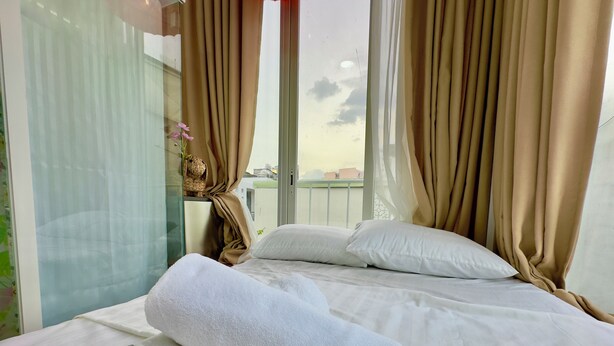 A hotel room with a bed, white pillows, and a rolled white towel. - Cherry Blossom Boutique Hotel (Ho Chi Minh City)