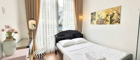 Un dormitorio ordenado con cama, mesita de noche y espejo.