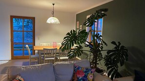 Un salon comprenant un canapé, une table à manger, des chaises et une grande plante.