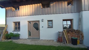 Une maison à deux étages, avec une façade blanche, une porte en bois et de nombreuses fenêtres.