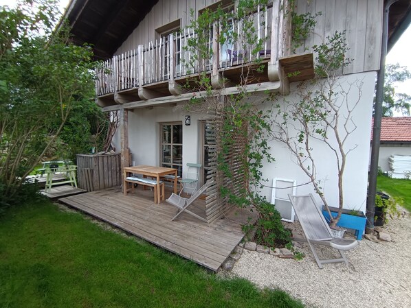 Una casa de madera con balcón, terraza de madera y un pequeño jardín.