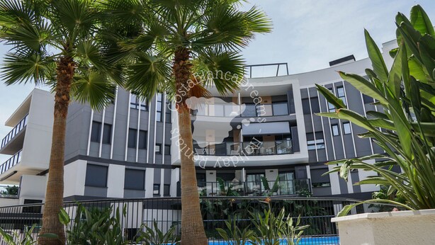 A modern building with a pool, palm trees, and a clear sky. - CostaBlancaDreams - Apartment Casobel in Javea (Javea / Xàbia)