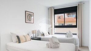 A hotel room with two beds, a nightstand, a lamp, a framed picture, and a window with curtains. - CostaBlancaDreams - Apartment Casobel in Javea (Javea / Xàbia)