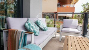 A balcony with a sofa, a wooden table, and a white chair. - CostaBlancaDreams - Apartment Casobel in Javea (Javea / Xàbia)