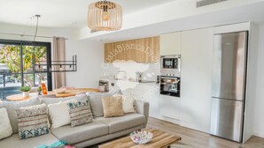 A modern living room with a sofa, coffee table, and a kitchen area with appliances. - CostaBlancaDreams - Apartment Casobel in Javea (Javea / Xàbia)