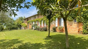 A brick building with a well-maintained lawn and a tree in the foreground. - Cottage with breathtaking views of the Pyrenees (Lézat-sur-Lèze)