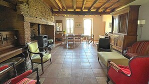 A rustic living room with a fireplace, wooden beams, tiled floor, and a dining area with chairs and a table. - Cottage with breathtaking views of the Pyrenees (Lézat-sur-Lèze)