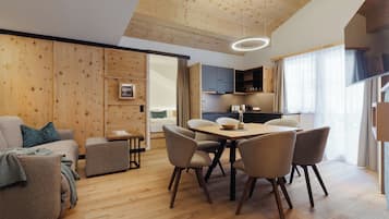 Una sala de estar moderna con techo de madera, un área de comedor con mesa y sillas, y una cocina al fondo.