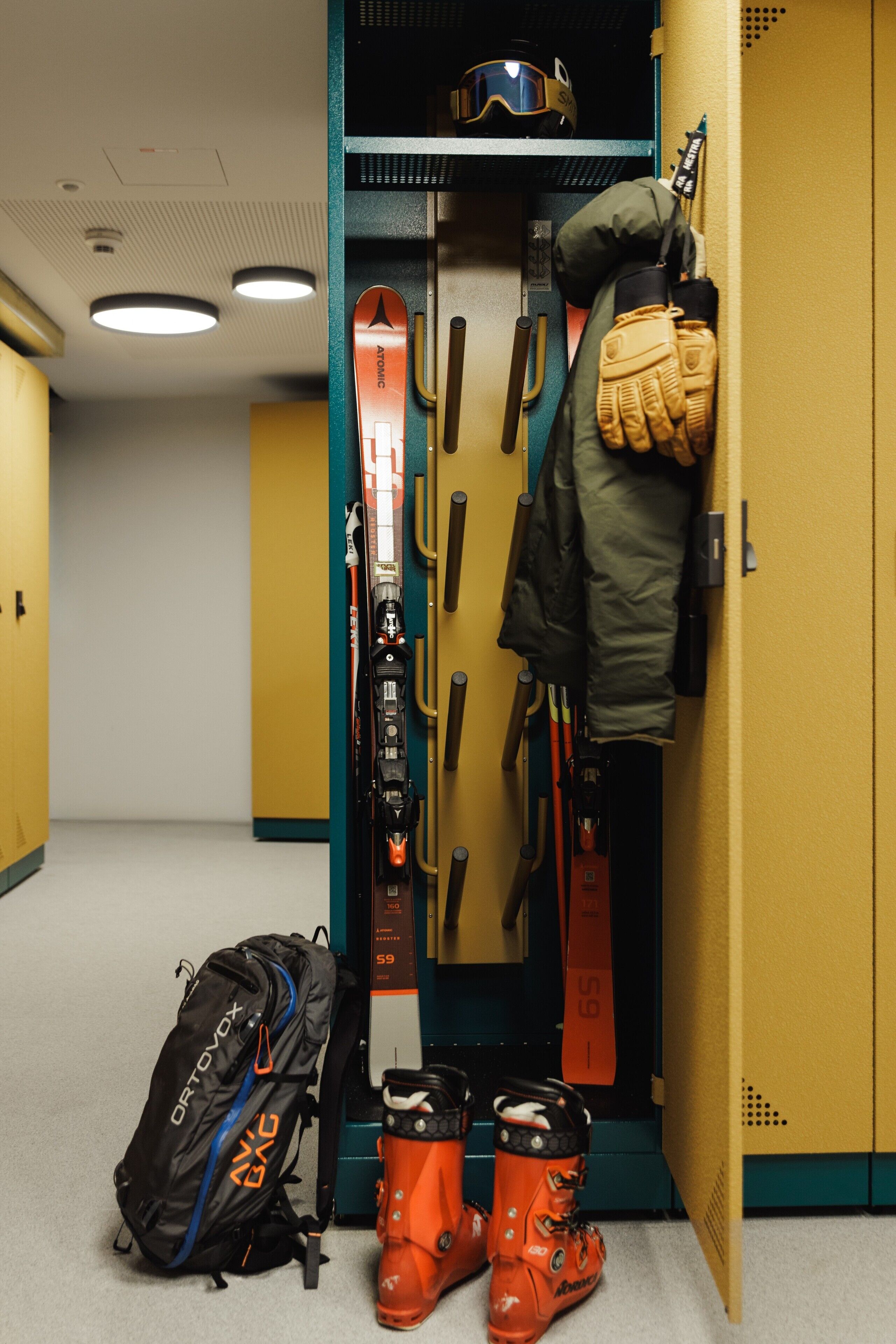 A storage area with skis, boots, and a backpack.