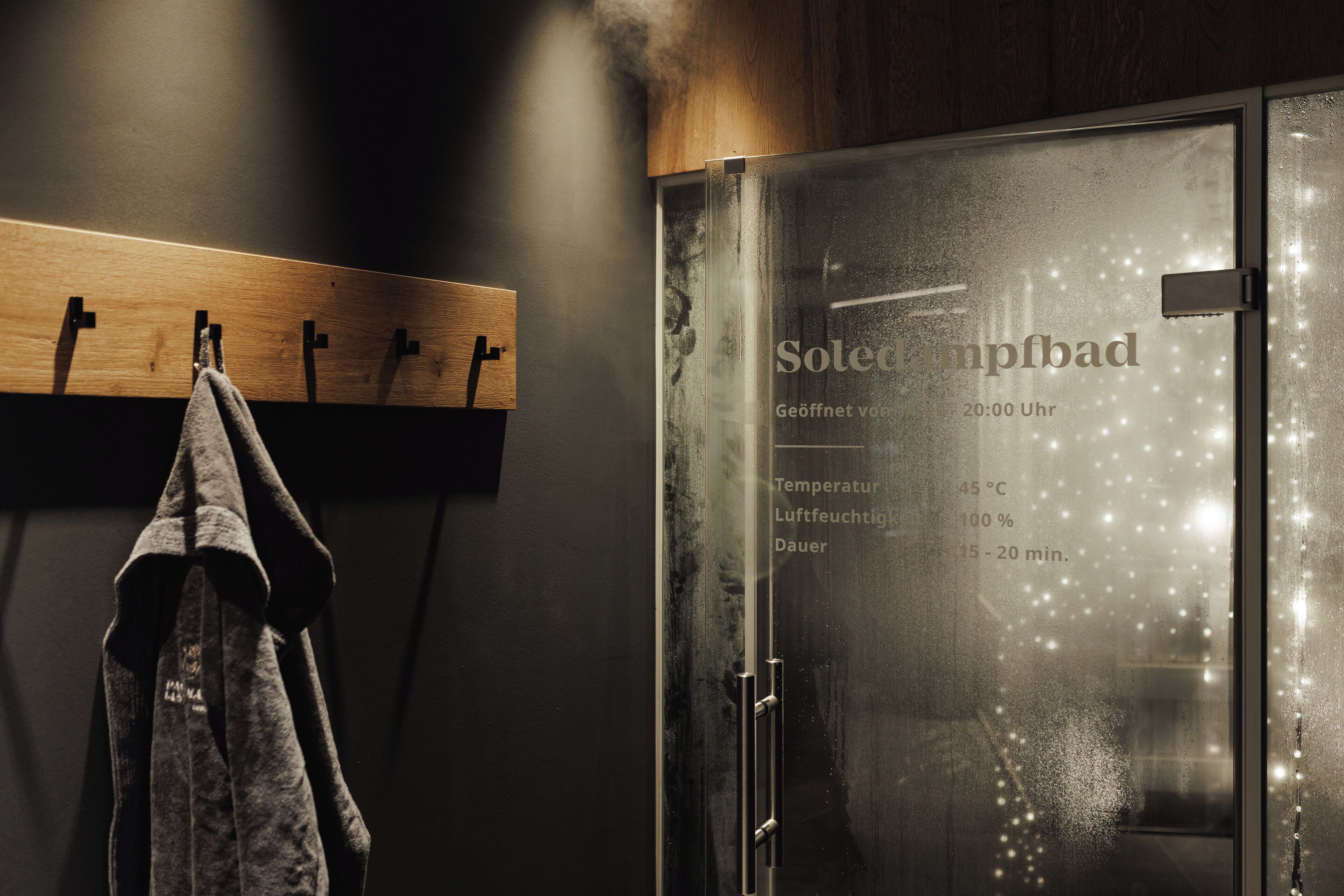 A sauna with a glass door displaying temperature, humidity, and duration settings.