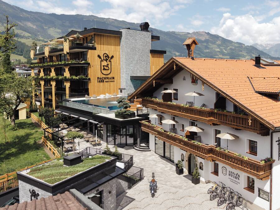 A hotel with a rooftop pool, outdoor seating, and mountain views.