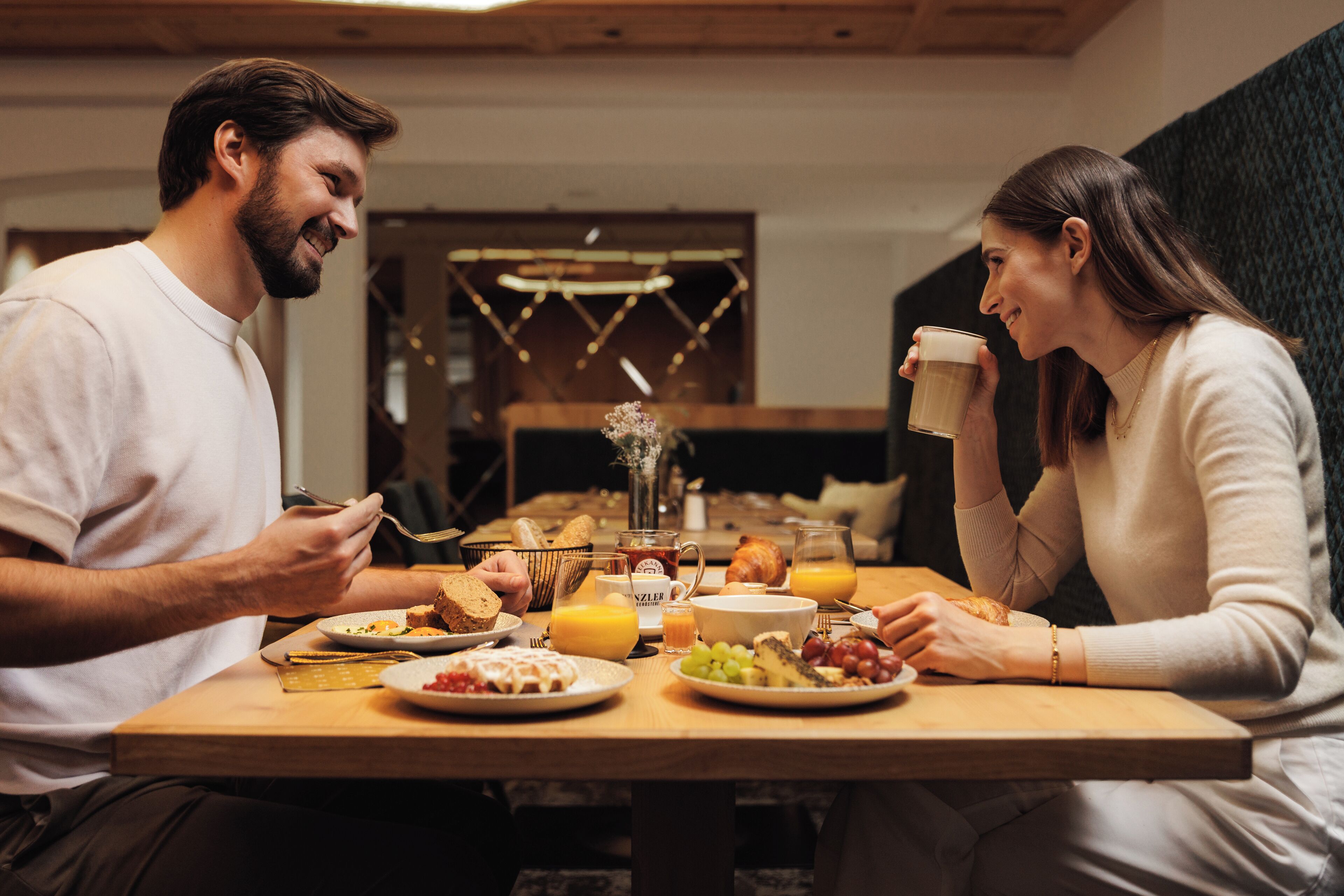 A breakfast setting with a wooden table, plates of food, and a cup of coffee.