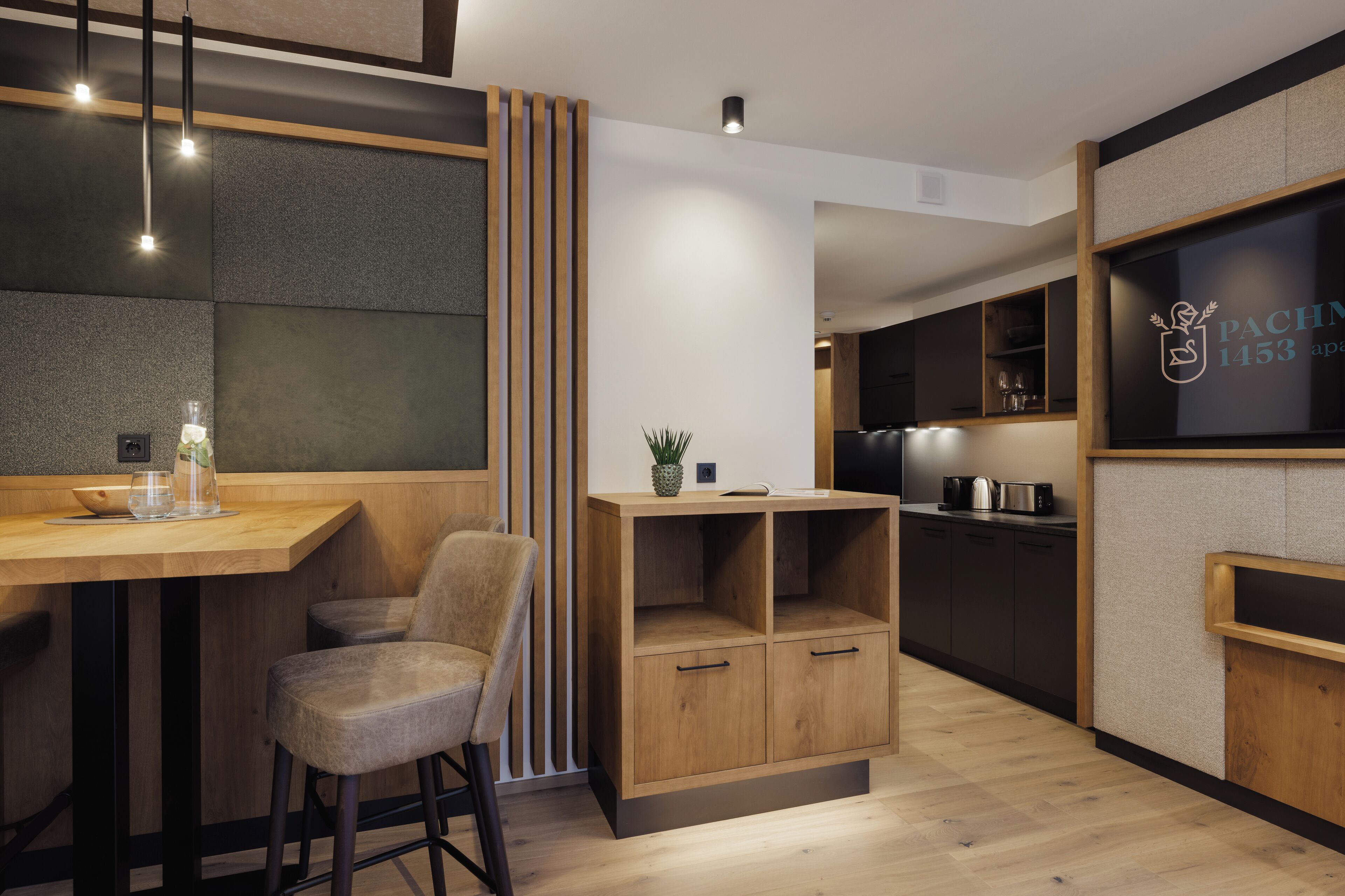 A modern kitchen with wooden cabinets, a bar area, and a seating space with a chair.