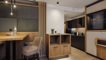 A modern kitchen with wooden cabinets, a bar area, and a seating space with a chair.