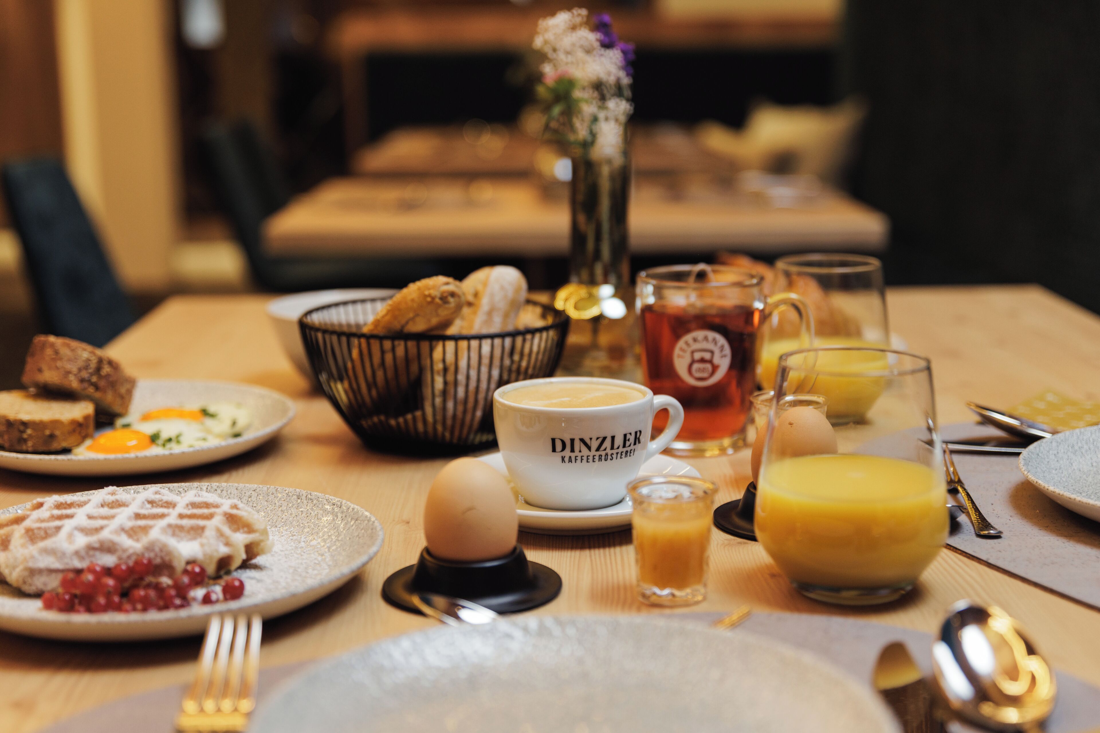 A breakfast table with various dishes including waffles, eggs, and coffee.