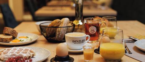 A breakfast table with various dishes including waffles, eggs, and coffee.