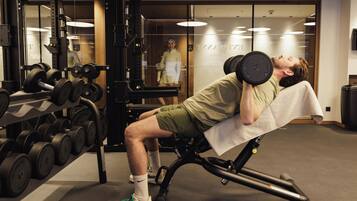 A gym with weightlifting equipment and a person lying on a bench.