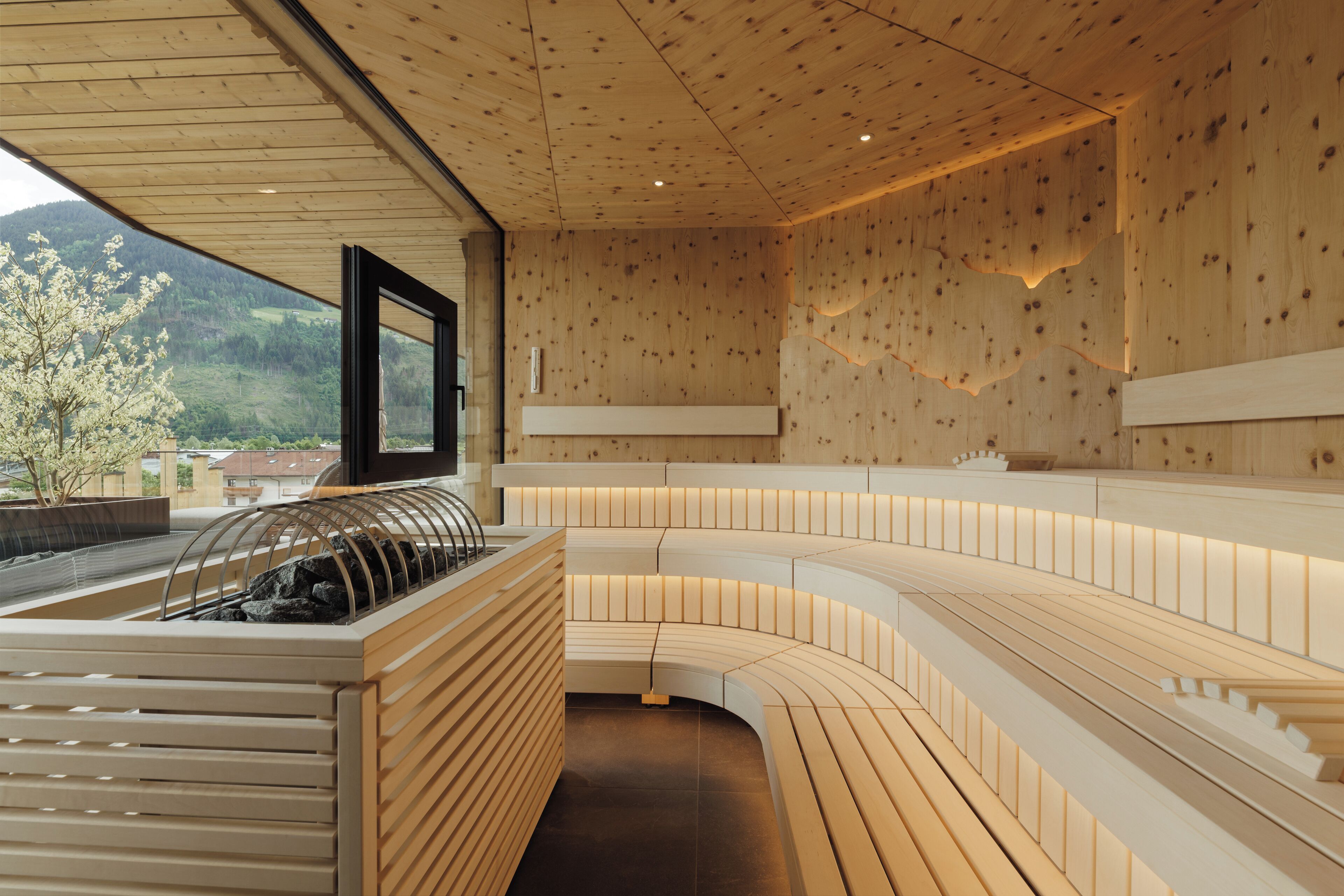A modern interior with wooden paneling, a curved seating area, and a view of a mountainous landscape.