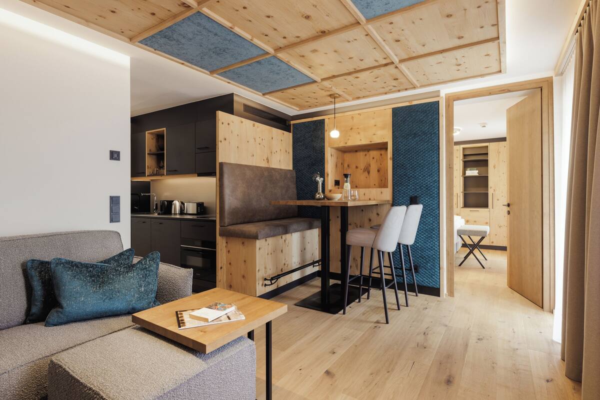 A modern living room with a wooden ceiling, a sofa, a coffee table, and a dining area with chairs and a table.