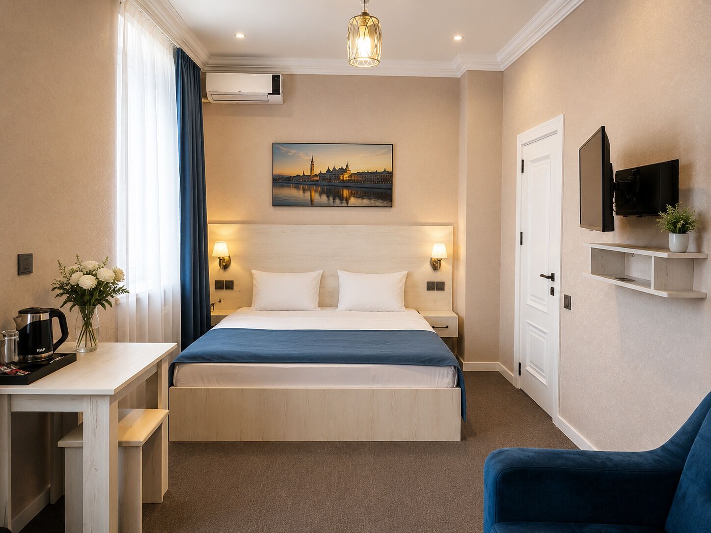 Hotellihuone, jossa on sänky, yöpöytälamput, työpöytä, kahvinkeitin, televisio ja taulu seinällä.