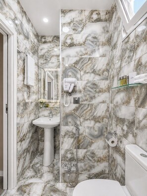 A bathroom with marble walls, a sink, a toilet, a shower, and a hairdryer. - Central Boutique Hotel Baku (Baku)