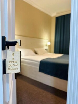 A hotel room with a bed, a bedside table with a lamp, and a door with a 'Please Do Not Disturb' sign. - Central Boutique Hotel Baku (Baku)