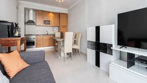 A modern living room with a grey sofa, a flat-screen TV, and a dining area with a table and chairs. - Platan Apartment, Portimão, Algarve (Portimão)