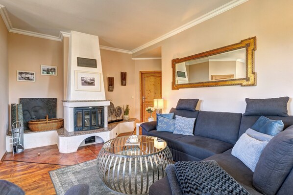 A living room with a fireplace, a large mirror, and a dark-colored sofa with blue cushions.