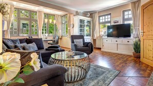 Un salón amplio con un ventanal grande, una mesa de centro de vidrio, un sofá y un televisor.