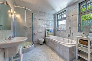 A modern bathroom with a large bathtub, a sink, and a toilet.