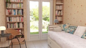 Une chambre à coucher avec un lit, une chaise, une table avec une lampe et deux étagères remplies de livres.