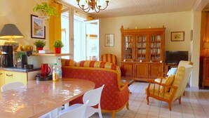 Un salon confortable avec un coin repas, une bibliothèque et un téléviseur.