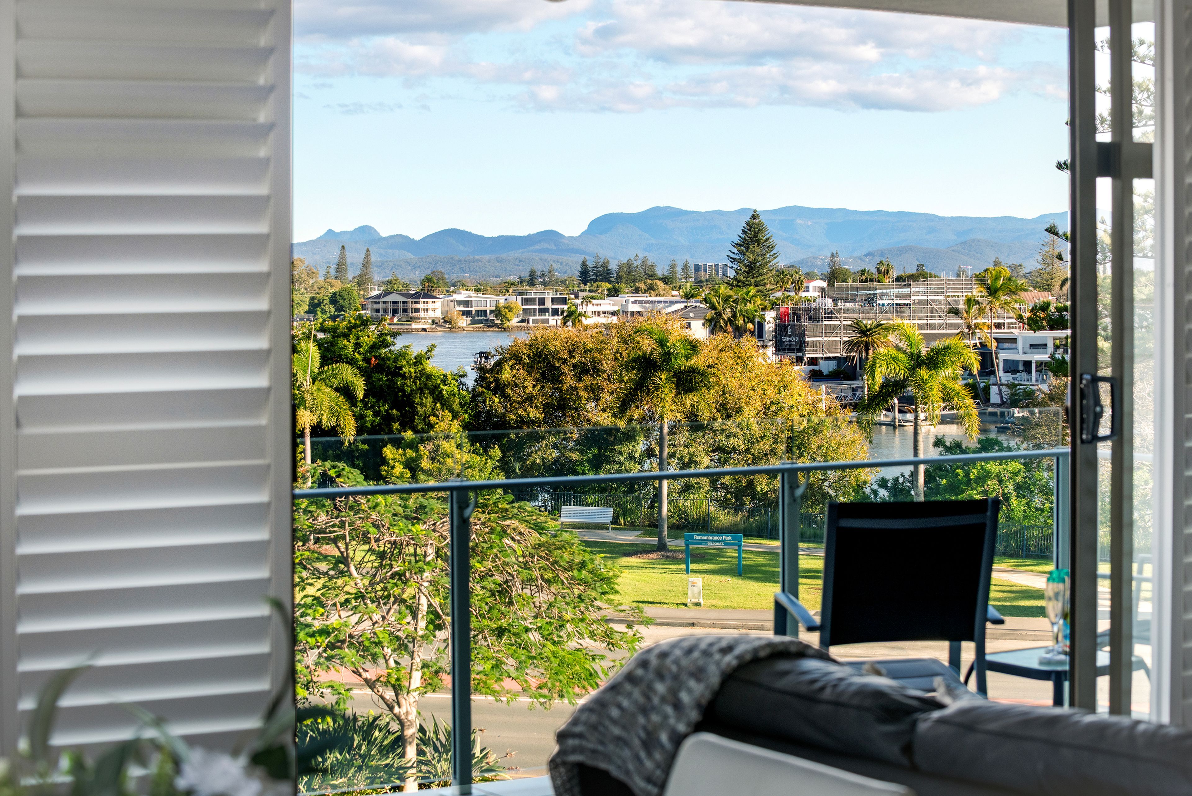 A balcony with a view of a residential area, a chair, and a table.